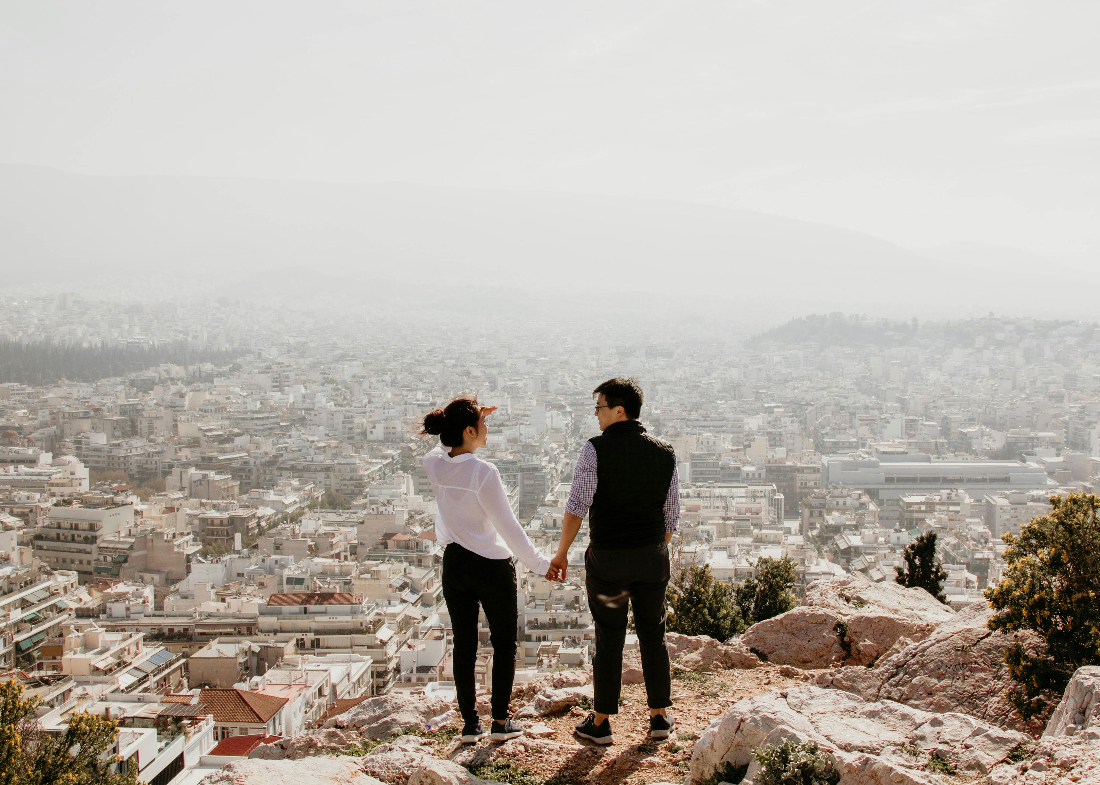 A couple standing on top of the mountain.